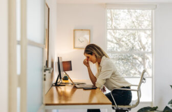 Woman holding her forehead while working at a home office