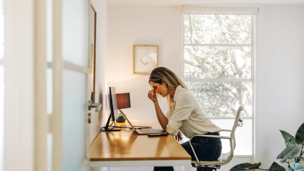 Woman holding her forehead while working at a home office